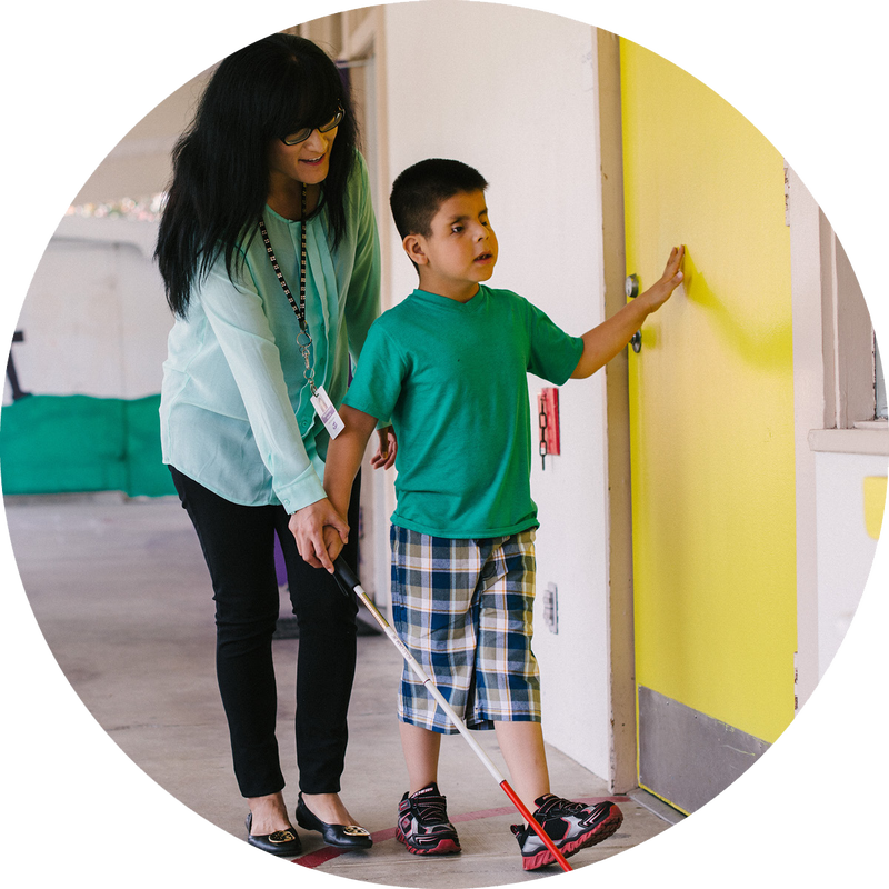 Mobility instructor teaches boy to walk with cane