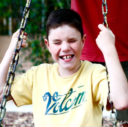 Visually impaired boy sits on swing set